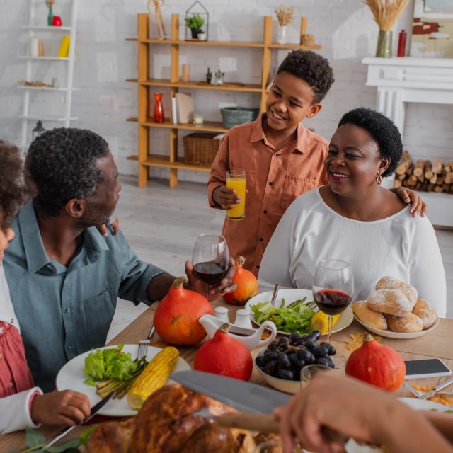 Smiling african american kids near grandparents and thanksgiving dinner at home Smiling african american kids near grandparents and thanksgiving dinner at home